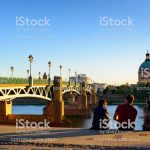 Toulouse, France - October 06, 2017: People are resting on the edge of the Garonne river against the Saint Pierre bridge and the dome of the Grave at the evening in Toulouse city of France.